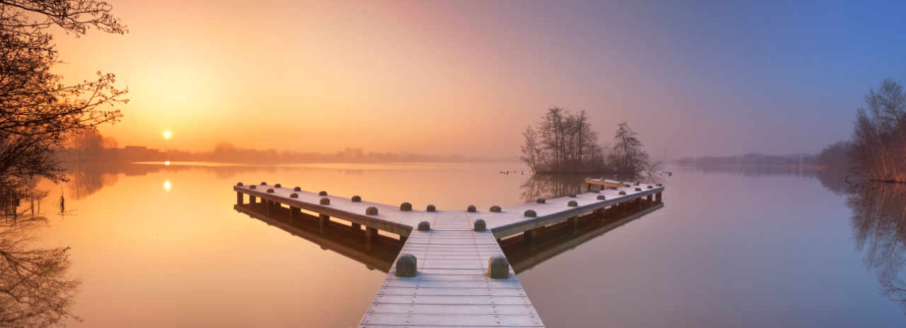 Y shaped landing stage jutting out into still lake at sunset